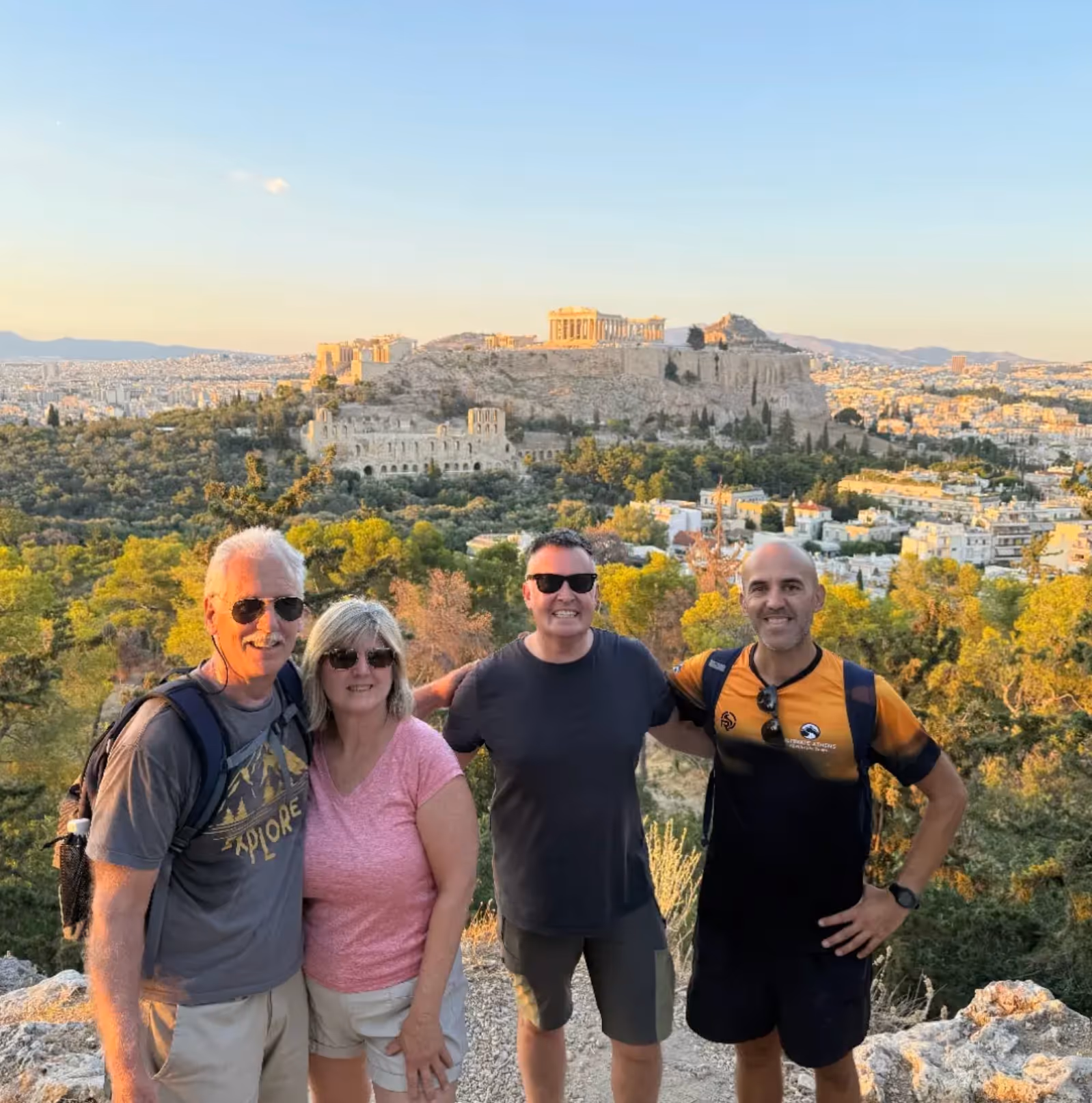 Small group of guests with their Athens tour leader, the Acropolis behind them at golden hour